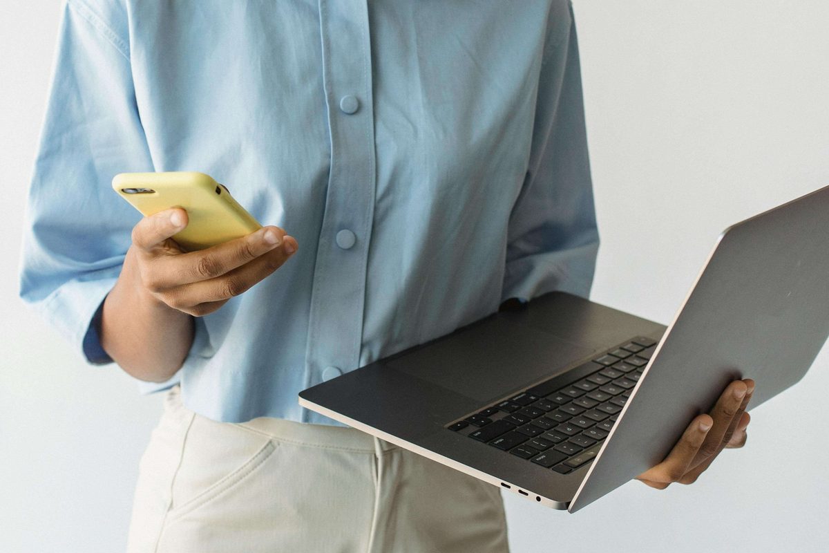 person working side hustle on laptop and phone